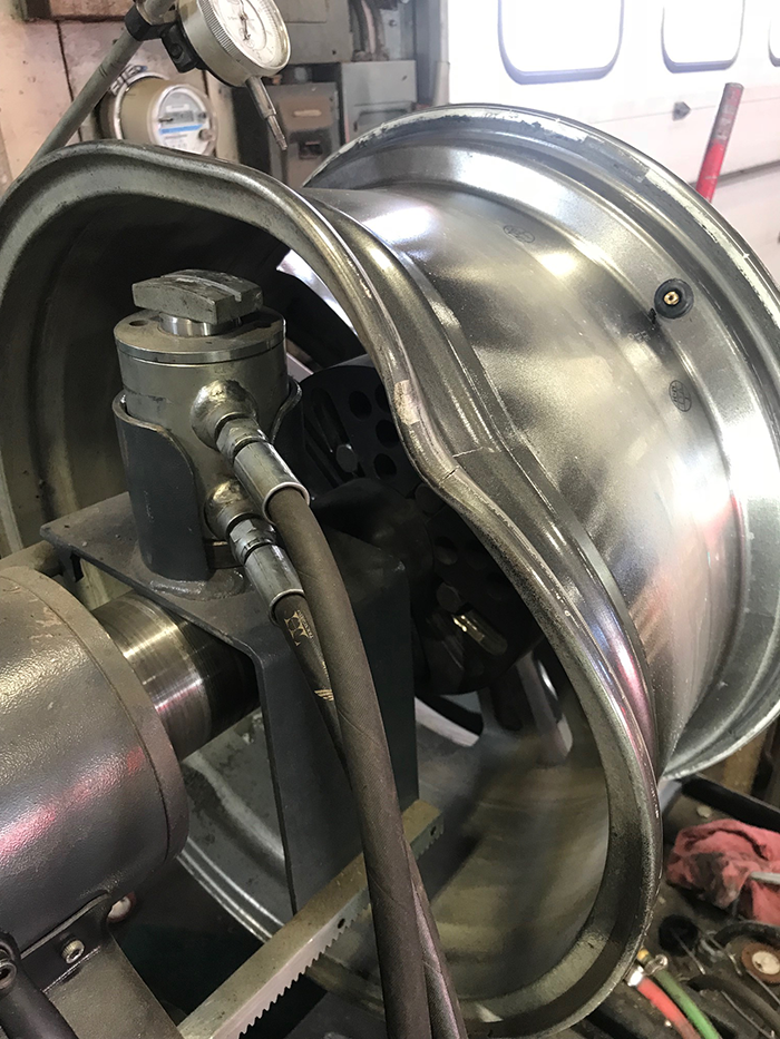 A very badly bent wheel rim is shown being straightened on the Nitromac machine.