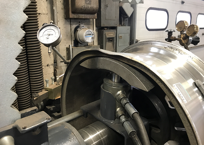 The bent wheel rim shown here is in the process of being straightened at Dias Spring Service.